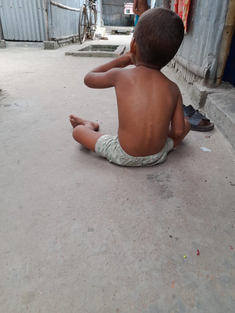 An unattended child eating rice from the floor.