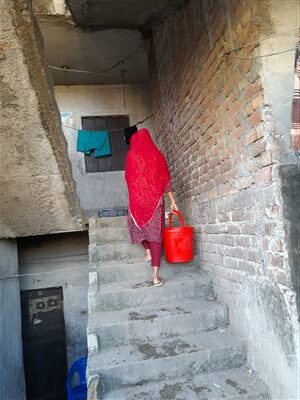 Aadya carrying water up the stairs in her building