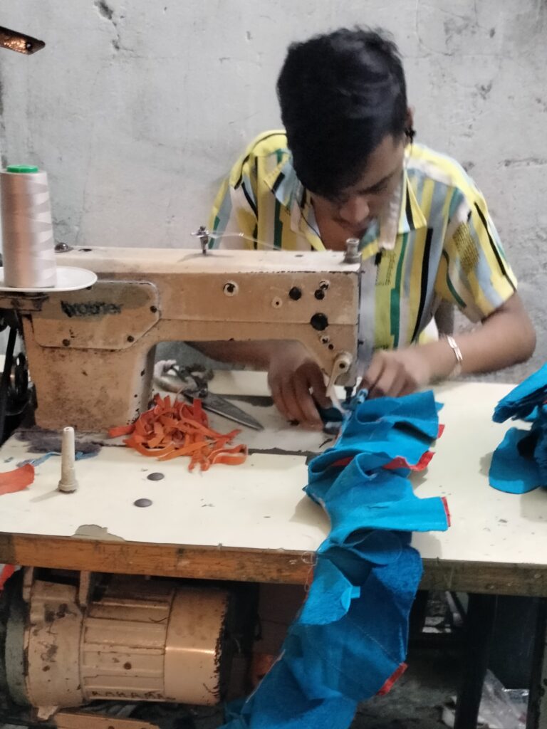 An adult worker sewing leather